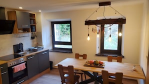 A modern kitchen with a dining table, chairs, and a window with a view of greenery.
