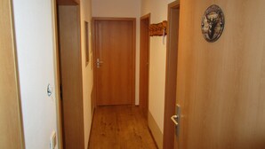 A narrow hallway with wooden doors and a welcome sign on one door.