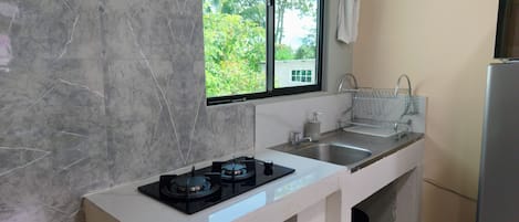 Una cocina con estufa a gas, dos fregaderos, una ventana y una toalla colgada en la pared.