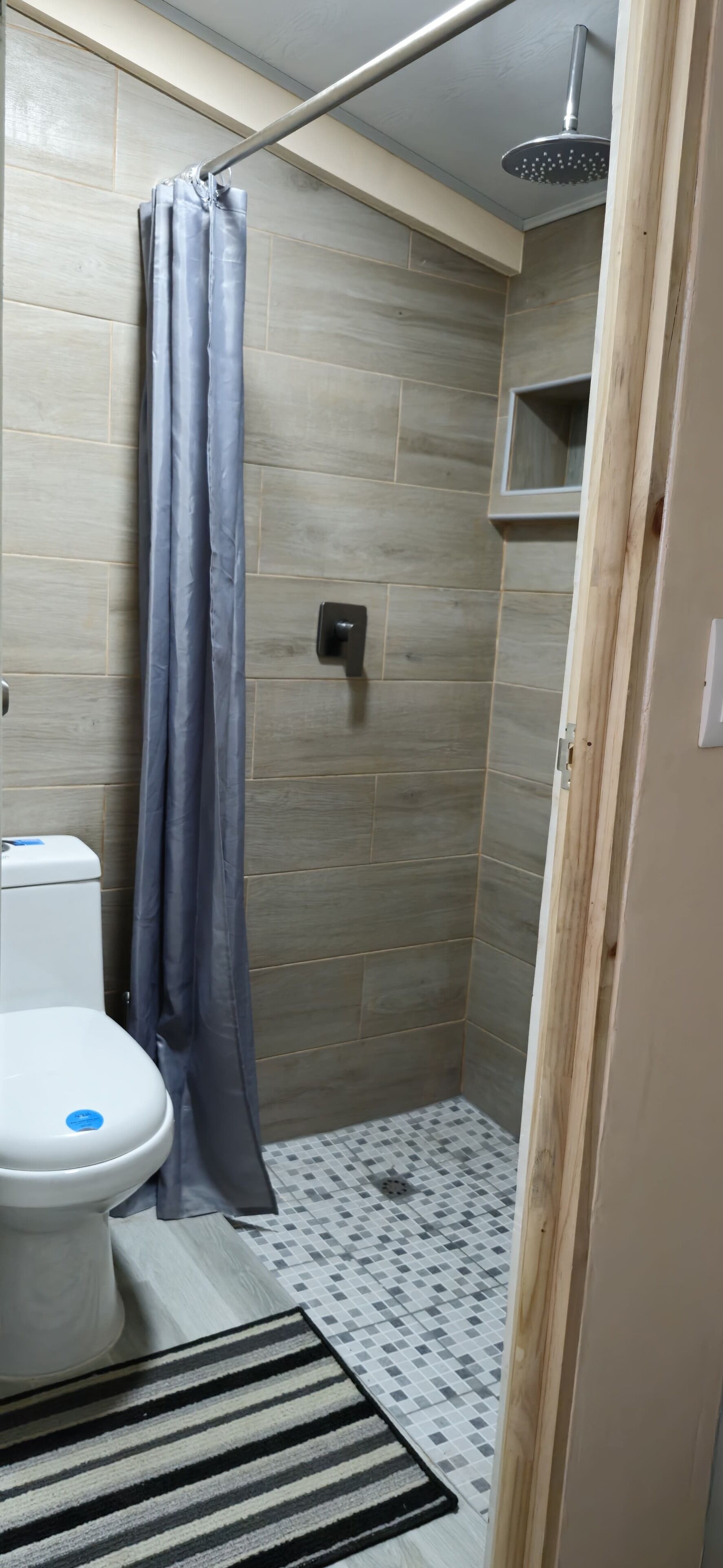 A bathroom with a shower, toilet, and a patterned floor.