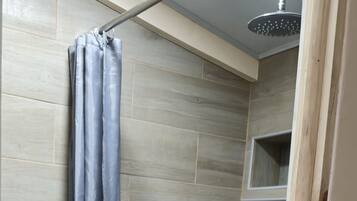 A bathroom with a shower, toilet, and a patterned floor.