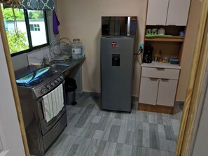 A compact kitchen with a stove, sink, refrigerator, and a microwave.