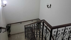 Una escalera con barandilla de metal, una planta en maceta y una lámpara fijada a la pared.