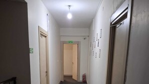 Un pasillo con pisos alfombrados, paredes blancas y puertas a ambos lados.