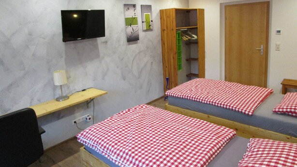 A bedroom with a bed, a TV, a desk, and a wardrobe. - Apartment "Unit 1" with Mountain View, Private Garden, and Wi-Fi (Bärenstein)