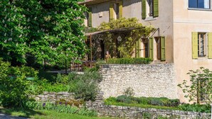 Ein traditionelles Steinhaus mit Garten, einer Pergola und einer Steinmauer.
