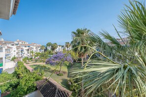 A residential area with buildings, a garden, and a palm tree. - Apartment in Puerto Banús (Marbella)