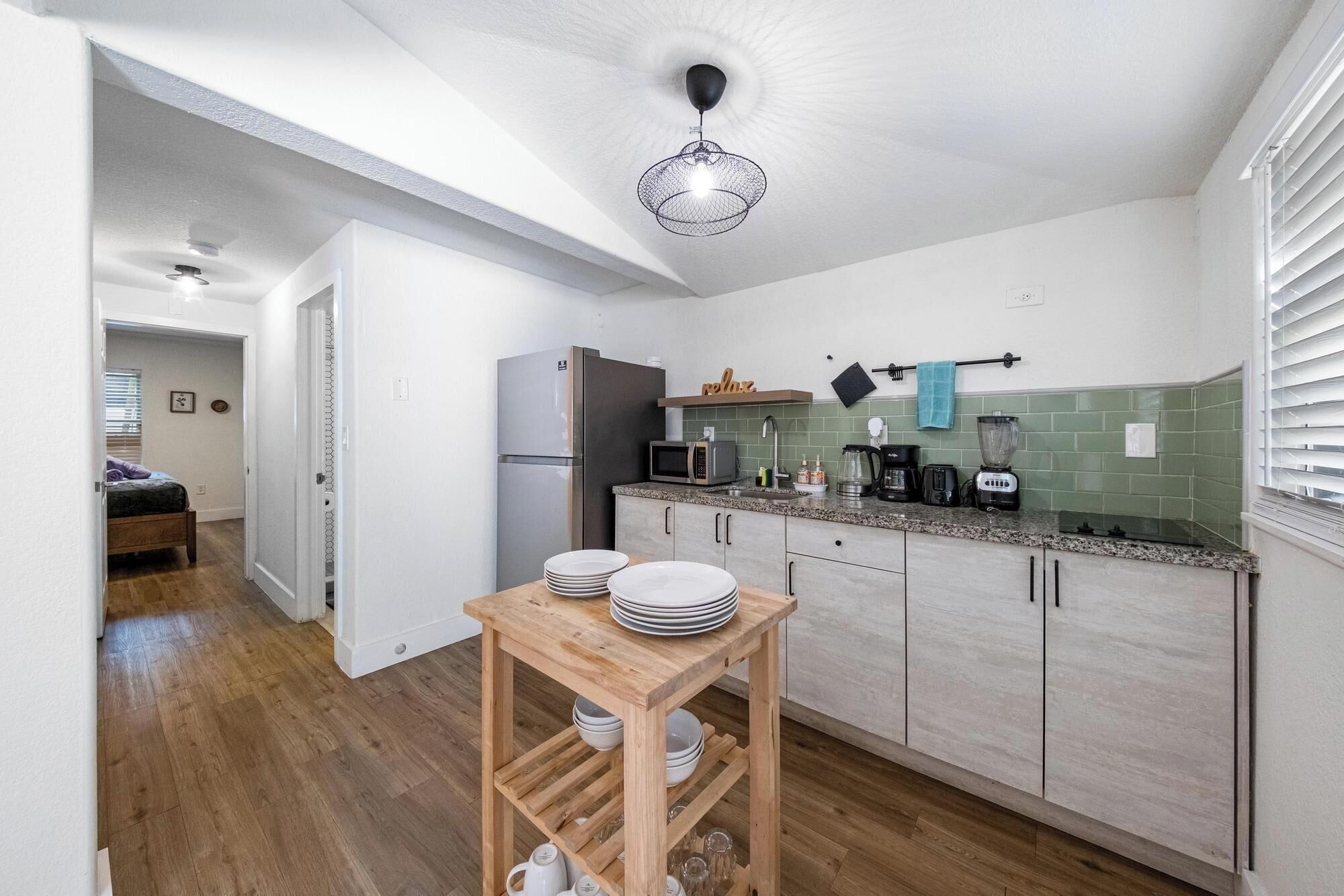 A compact kitchen with a refrigerator, microwave, coffee maker, and a sink.