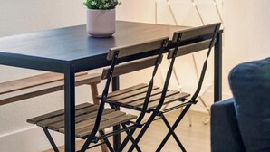 Un comedor con una mesa, sillas, una planta en maceta y un cuadro en la pared.
