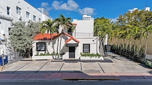 A white building with a red-tiled roof, a small entrance, and a staircase leading to the upper floor. - Art Deco Stay 1 Block From Ocean Balcony (Miami Beach)