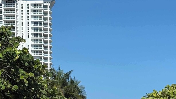A pathway with directional signs, a palm tree-lined sidewalk, and a tall building in the background. - Art Deco Stay 1 Block From Ocean Balcony (Miami Beach)