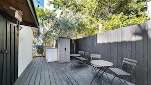 A wooden deck with a table and chairs, a small shed, and a wooden fence. - Art Deco Stay 1 Block From Ocean Balcony (Miami Beach)