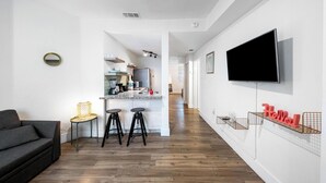 Een moderne woonruimte met een keuken, een eethoek en een aan de muur bevestigde televisie.