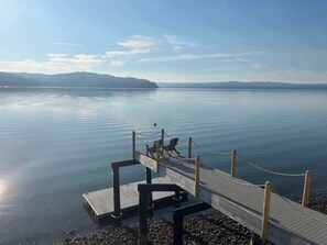 A wooden pier extending into calm water with a chair and a rope barrier. - Waterfront Retreat - Hot Tub Fireplace Pier (Shelton)