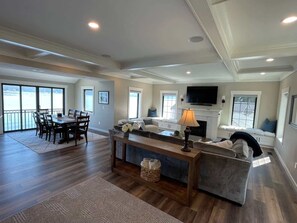 A spacious living room with a fireplace, a dining area with a large table and chairs, and a balcony with large windows. - Waterfront Retreat - Hot Tub Fireplace Pier (Shelton)