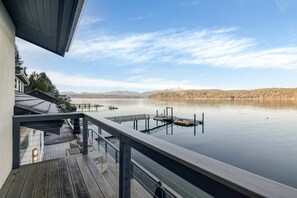 Eine Holzterrasse mit Blick auf einen ruhigen See und ferne Berge.