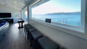 A modern room with a large window offering a view of a body of water and distant land. - Hood Canal Waterfront - Dock Hot Tub BBQ Games (Union)