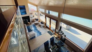 A spacious living area with a large window overlooking a body of water, a fireplace, and a dining area with a glass table. - Hood Canal Waterfront - Dock Hot Tub BBQ Games (Union)