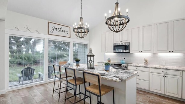 A kitchen with a large island, white cabinets, and two chandeliers. - Fore-Shore | Sawgrass CC Golf View Retreat | 3RB - 2BA | Walk to the Beach (Ponte Vedra Beach)