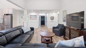 A modern living room with a sofa, armchair, and coffee table. There is a TV and a cabinet. - Fore-Shore | Sawgrass CC Golf View Retreat | 3RB - 2BA | Walk to the Beach (Ponte Vedra Beach)