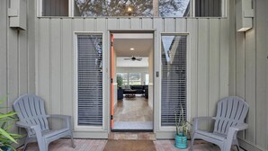A house entrance with a sliding glass door, two Adirondack chairs, and a potted plant. - Fore-Shore | Sawgrass CC Golf View Retreat | 3RB - 2BA | Walk to the Beach (Ponte Vedra Beach)