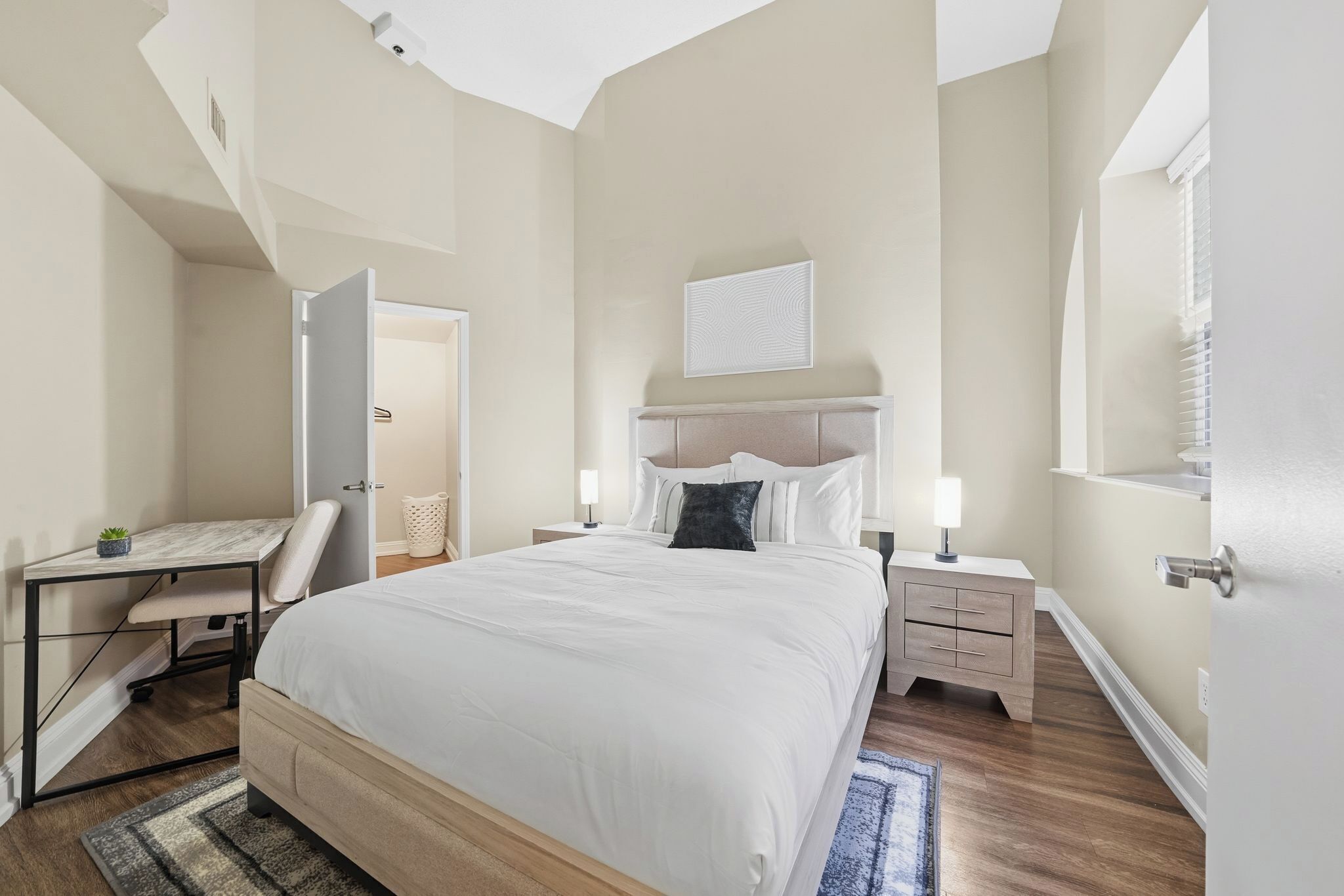 Une chambre à coucher comprenant un lit, des tables de chevet, un bureau et une chaise.
