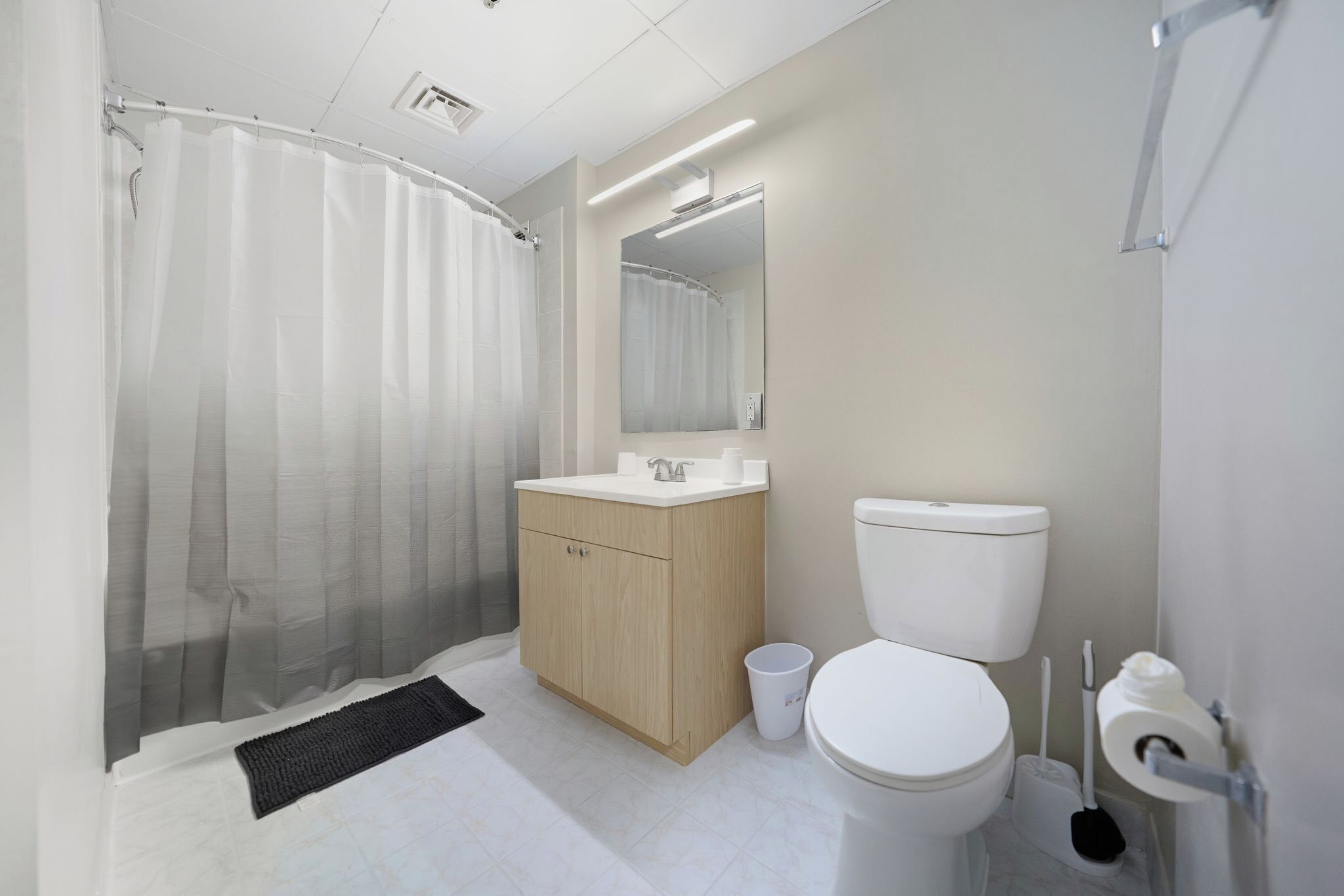 A modern bathroom with a shower, toilet, sink, and mirror.