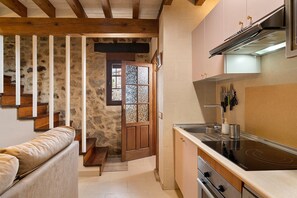 A narrow hallway leading to a kitchen with a built-in stove, a bench, and a door with frosted glass panels. - Casa Rural 'Quimera' with Mountain Views and Balcony (Gil-García)