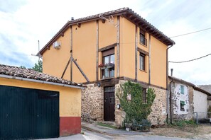 A two-story building with a yellow facade, a stone base, and a tiled roof. - Casa Rural 'Quimera' with Mountain Views and Balcony (Gil-García)