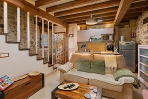Una sala de estar acogedora con un sofá, una mesa de centro de madera y una zona de cocina con microondas y refrigerador.