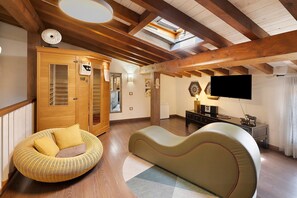 A spacious room with a high ceiling, wooden beams, a large window, a sofa, a wicker chair, a television, and a wooden wardrobe. - Casa Rural 'Quimera' with Mountain Views and Balcony (Gil-García)