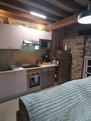 Une cuisine avec des poutres en bois, un four à micro-ondes, une machine à café et un réfrigérateur.