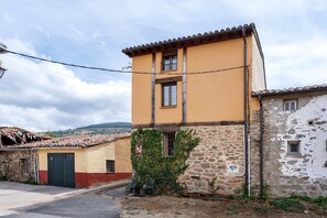 A two-story building with a stone base and a yellow upper section, featuring a small window and a door. - Casa Rural 'Quimera' with Mountain Views and Balcony (Gil-García)