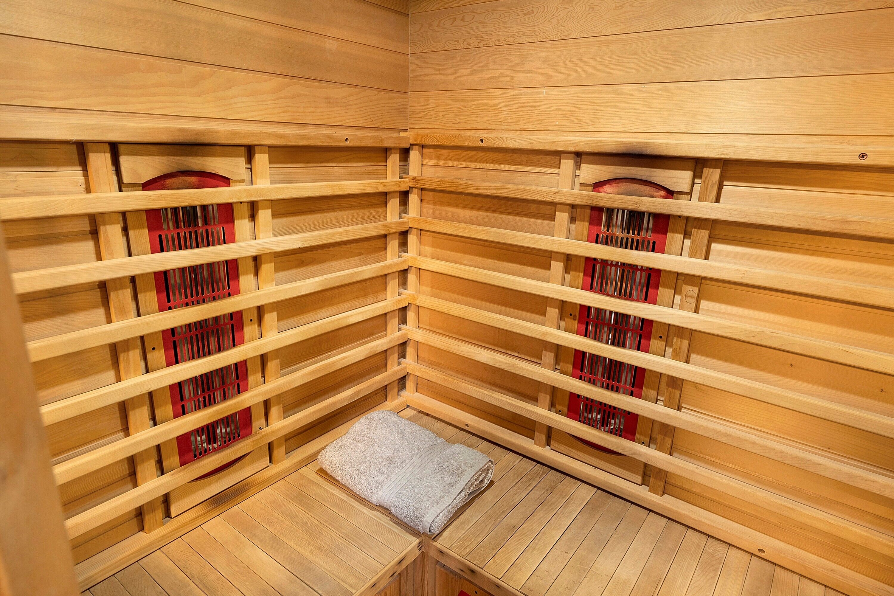 Un sauna avec des murs et des bancs en bois, une serviette sur le sol et des grilles de ventilation.