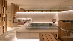 A modern spa room with a wooden bench, a hot tub, and a seating area with towels. - Chalet Acorn 4 bedroom with SPA (Chamonix)