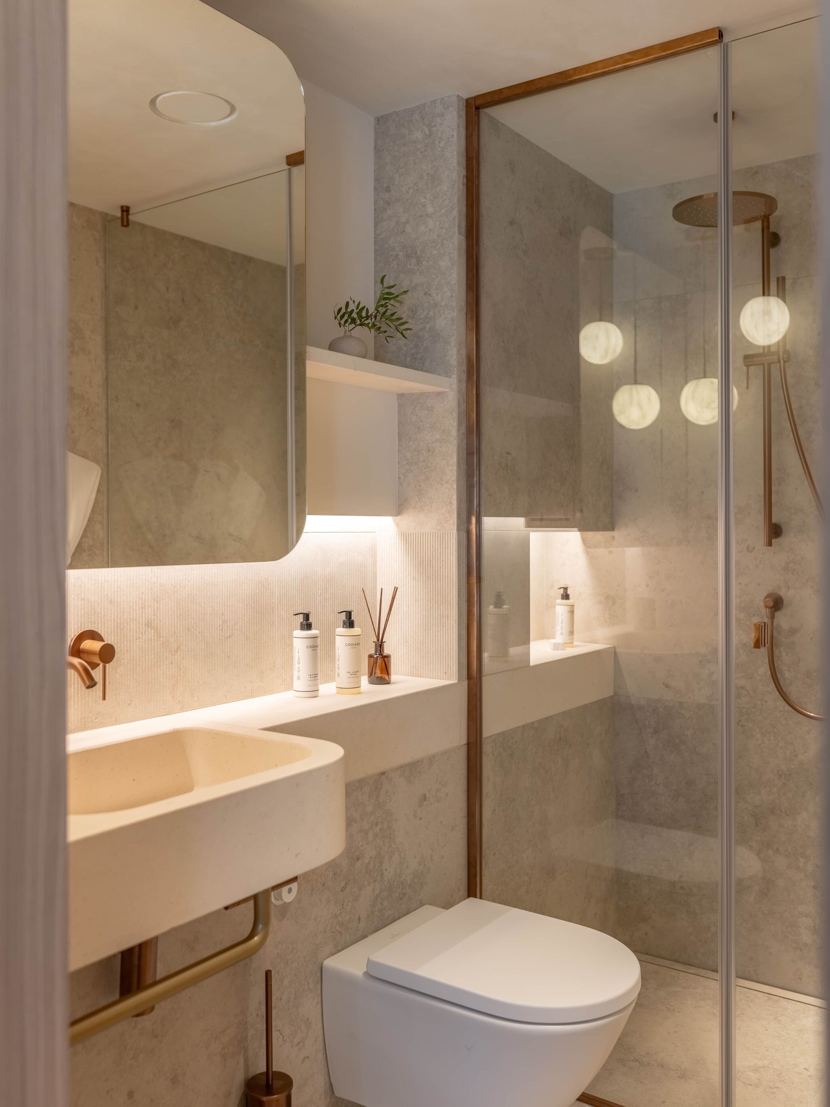 A modern bathroom with a glass-enclosed shower, a white sink, and a toilet.