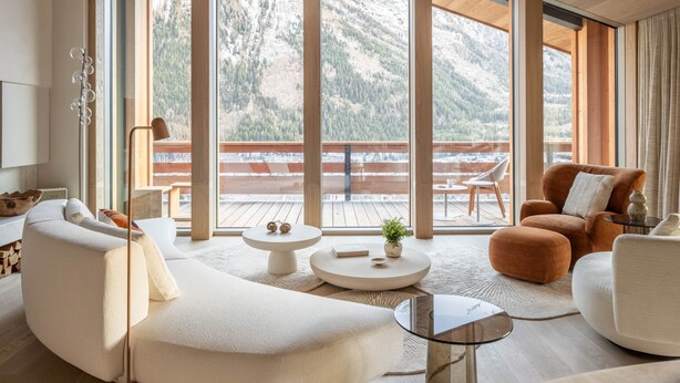 A modern living room with large windows, a wooden deck, and a mountain view. - Chalet Acorn 4 bedroom with SPA (Chamonix)
