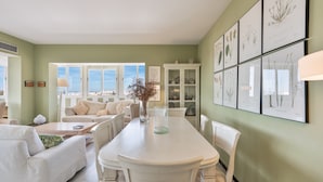A spacious room with a dining table, white furniture, and framed botanical prints on the wall. - Marbella Center – 350m from the Beach (MARBELLA)