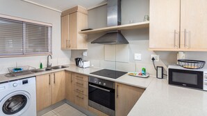 Cocina compacta con lavadora, horno, microondas y pileta.