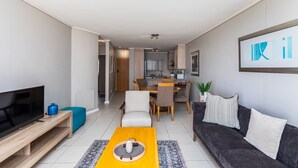 Una sala de estar moderna con televisor, sofá, mesa de centro y comedor.