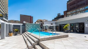 Ein Pool auf dem Dach mit Stufen, umgeben von modernen Gebäuden.