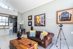 Ein modernes Wohnzimmer mit einer Ledersofa, einem Holztisch und gerahmten Kunstwerken an der Wand.