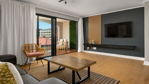 A modern living room with a sofa, a wooden table, and a TV mounted on the wall. - Rockwell 220 by Ctha (Cape Town)