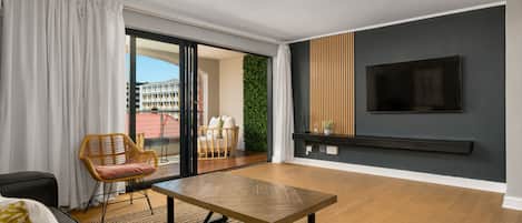 A modern living room with a sofa, a wooden table, and a TV mounted on the wall.
