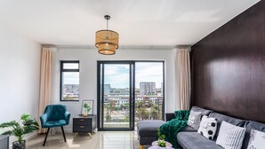 A modern living room with a sofa, a chair, a small table, and a view through large windows. - Knightsbridge 702w by Ctha (Cape Town)
