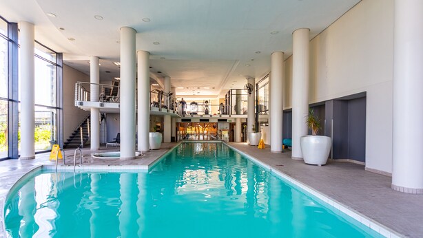 An indoor swimming pool with multiple levels, large pillars, and a staircase leading to an upper deck. - Knightsbridge 702w by Ctha (Cape Town)