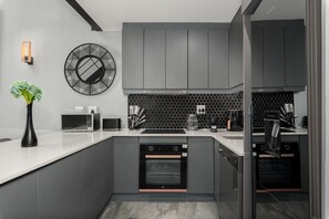 A modern kitchen with grey cabinets, a microwave, a coffee maker, and a dishwasher.
