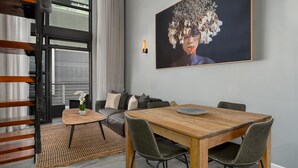 Ein modernes Wohnzimmer mit einem Holzesstisch, einem grauen Sofa und einem großen Blumenbild an der Wand.