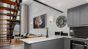 Eine moderne Küche mit grauen Schränken, einer weißen Arbeitsplatte, einem schwarzen Backofen und einer schwarzen Spritzschutzwand.