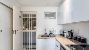 A compact kitchen with a sink, a toaster, a kettle, and a stove. - First Beach 203 by Ctha (Cape Town)